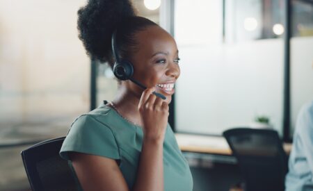Woman in blue shirt smiling and talking into headset