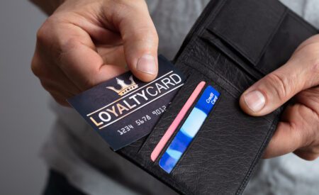 Closeup of hands placing a loyalty credit card into a wallet