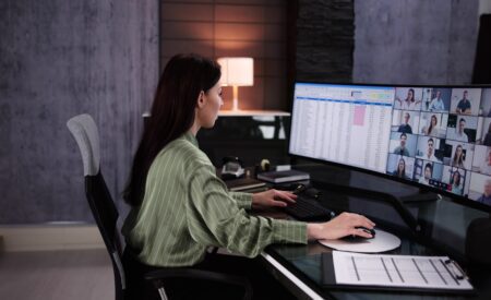 Woman working at a desk with two computer monitors