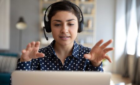 Woman wearing headset while talking and working on a computer