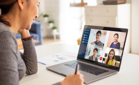 Woman talking to colleagues and smiling while on a video call